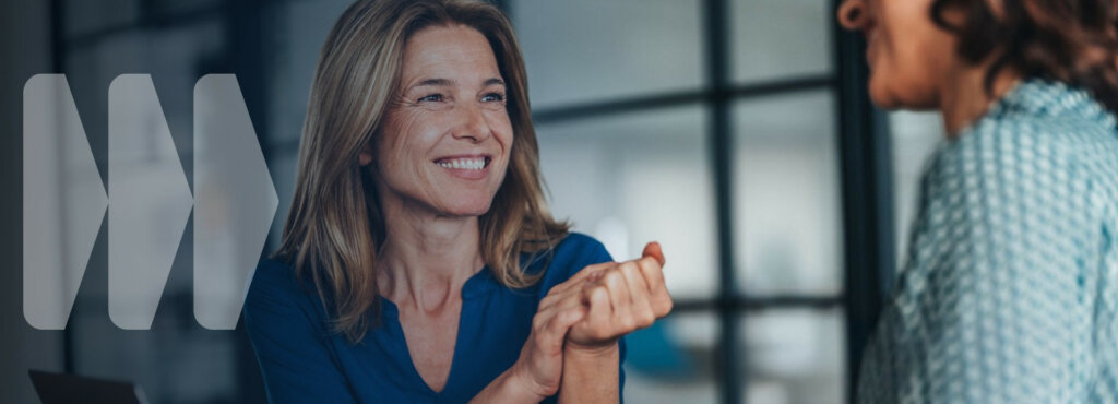 Nainen toimistossa katsoo ja hymyilee.