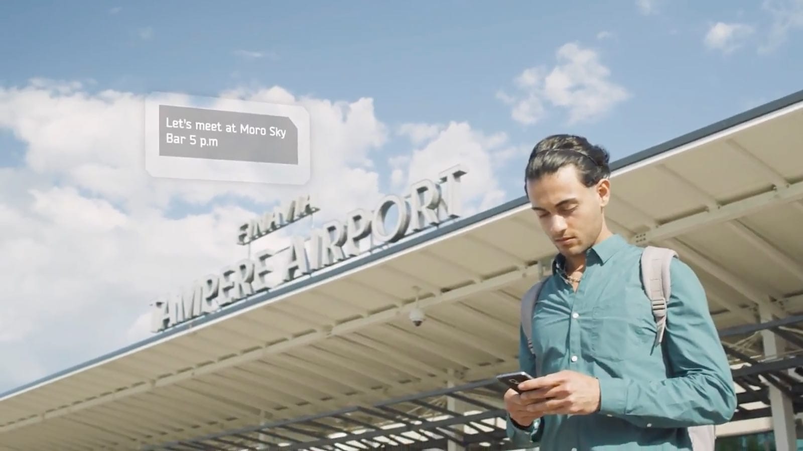 Kuva miehestä lukemassa viestiä puhelimestaan Pirkkalan lentokentällä.
